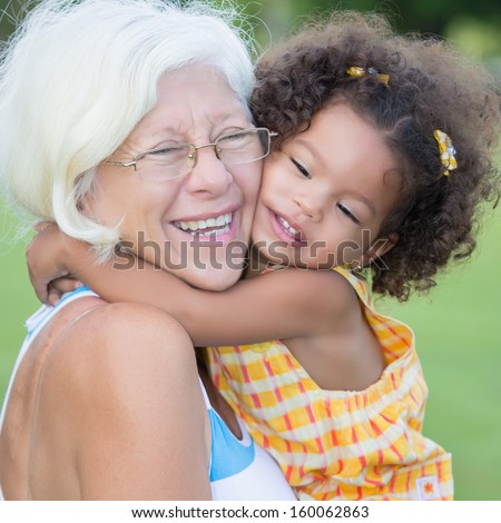 Grandmother Hugs Her Hispanic Granddaughter On A Park