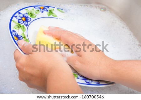 Hands washing the dishes on soapy water