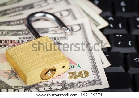 Open padlock and a stack of money on a black computer keyboard