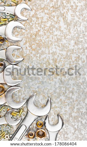 Set of tools wrenches, screws and nuts framing a textured background with space for text