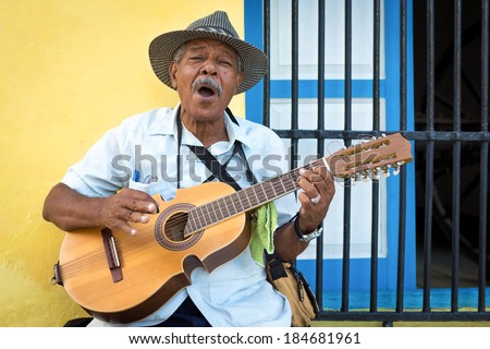 HAVANA, CUBA - FEBRUARY 25, 2014: Street musician playing traditional cuban music on an acoustic guitar for the entertainment of tourists in a typical colorful Old Havana street