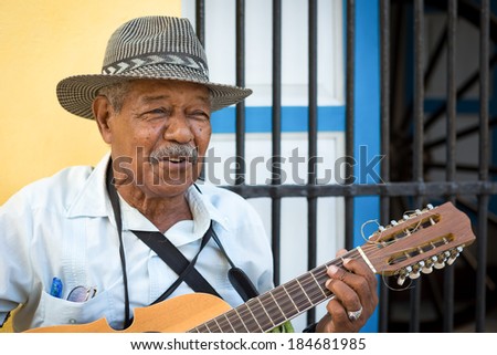 HAVANA, CUBA -?? FEBRUARY 25, 2014: Street musician playing traditional cuban music on an acoustic guitar for the entertainment of tourists in a typical colorful Old Havana street