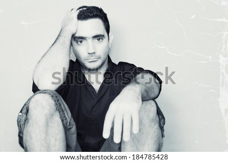 High key portrait of a sad young man sitting on the floor