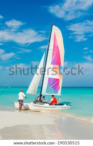 VARADERO,CUBA - APRIL 28,2014 : Tourists boarding a colorful sailing boat on a beautiful sunny day at the beach