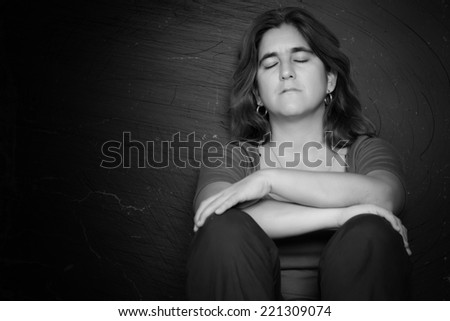 Dramatic black and white portrait of a sad and depressed woman with a grunge background