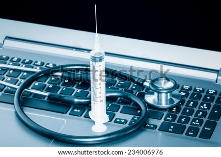 Computer system health or auditing - Stethoscope and syringe over a computer keyboard toned in blue