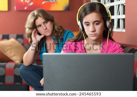 Computer addiction - Teenage girl using a laptop and ignoring her worried mother