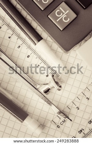 School supplies on a checked notebook background toned in sepia