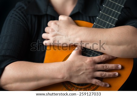 Classic guitar closeup - Musician hands embracing a classic acoustic guitar