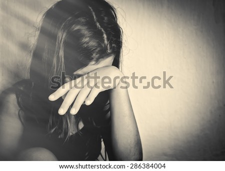 Monochrome portrait of a sad and lonely girl crying with a hand covering her face (with space for text)