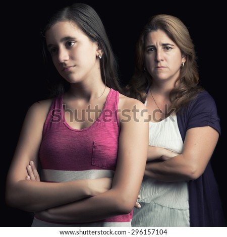 Teenage girl and her mother sad and angry at each other isolated on black
