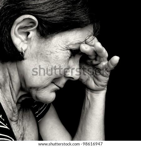 Black and white portrait of a depressed old  woman suffering from stress or a strong headache isolated on black