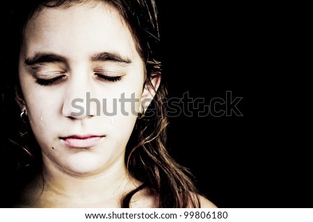 Dramatic portrait of a very sad girl crying isolated on black with space for text