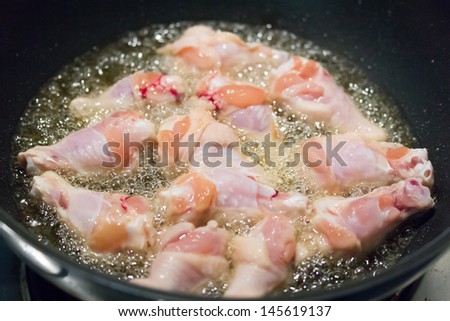 cooking raw chicken thighs fried in hot oil pan