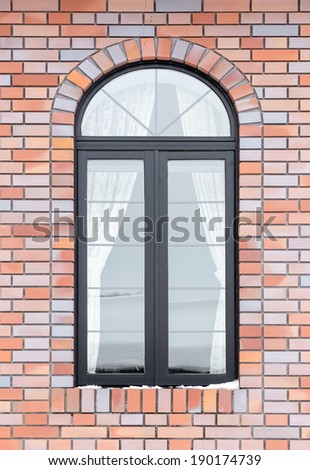 painted wood arched window in a red brick wall