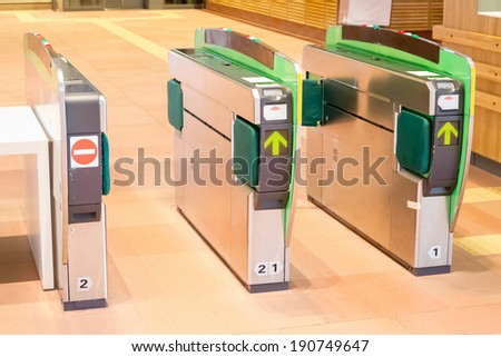 Turnstiles in underground railway station. Green arrows pointing to the way forwards. green barriers preventing progress