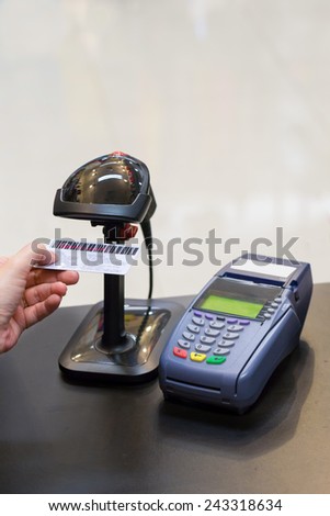 Cashier\'s hand scanning barcode on member card with credit card machine on the counter
