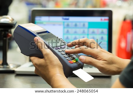 man\'s hand with credit card swipe through terminal for sale in store