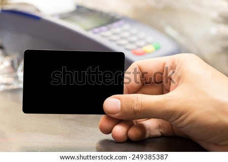 close up of man hand holding blank card with credit card machine in background