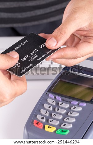 Credit Card Machine on the Table with Woman handing over credit card to Cashier in Background