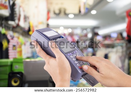 Woman hand with credit card swipe through terminal for sale in Clothes Store