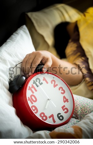 Man sleeping in bed turning off an alarm clock in the morning
