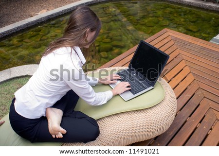 Female in business attire working on her laptop while seated outside