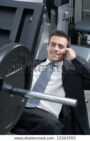 A businessman, at a gym, talking on cellphone waiting for a friend.