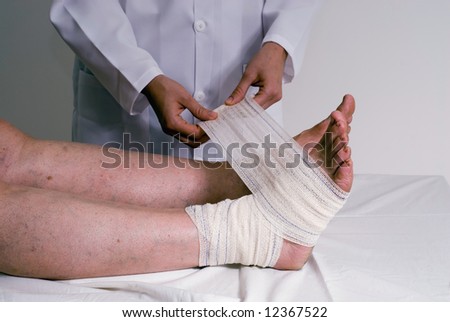 An isolated shot of a doctor/nurse hands bandaging a women\'s sprained ankle.