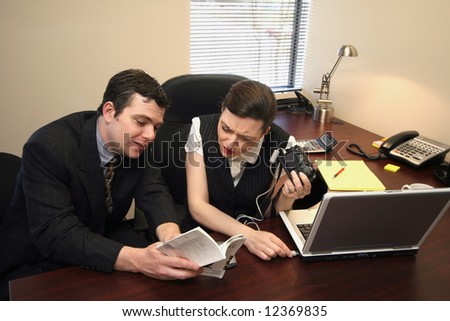 Male and female colleagues trying to figure out how to connect a digital camera to a laptop