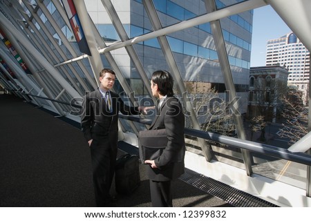 Two men in business suits chatting in an urban walkway on a sunny day