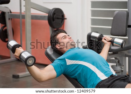 Young, athletic man in the gym doing a chest press on a weight bench