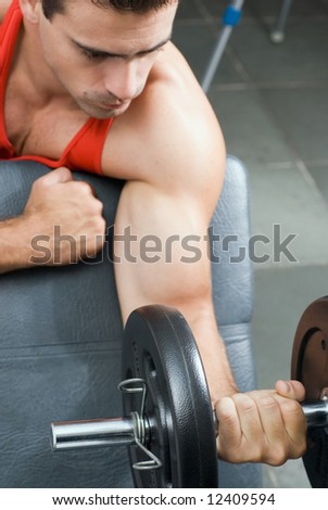 A shot of a male weightlifter doing a bicep curl with a barbell.