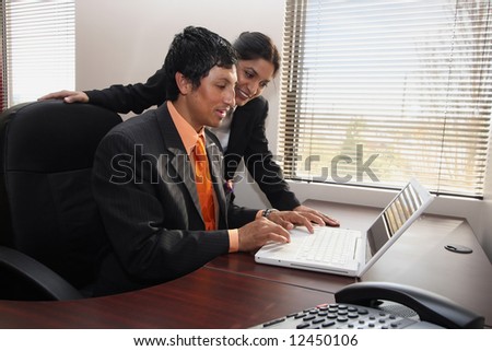 Male and female business colleagues working together on a laptop and pleased with their progress