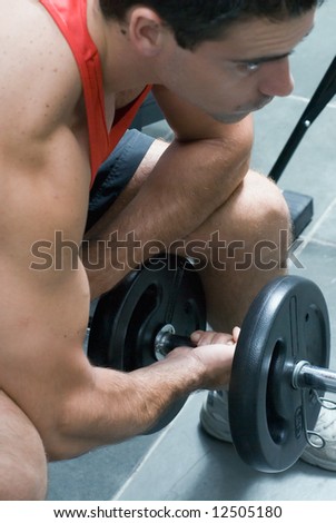 A shot of a male weightlifter doing a bicep curl with a barbell.