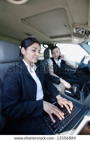Two businesswomen working on a laptop in a mobile office in a car