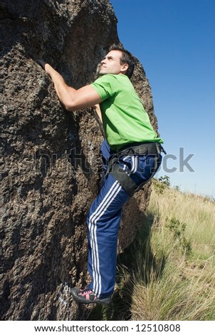 Athletic young man climbing on the face of a rock wall. Shot is taken from the side