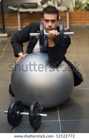 stock-photo-attractive-young-executive-doing-biceps-curls-in-a-gym-dressed-in-a-business-suit-his-face-is-12522772.jpg