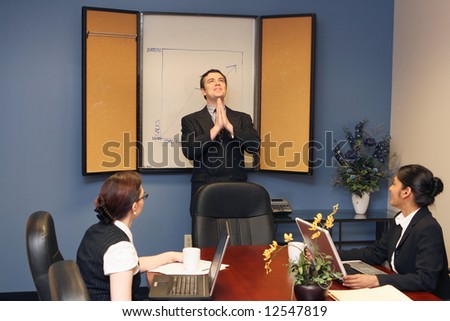 Businessman presenting to his colleagues staring up at the ceiling with his hands joined in prayer