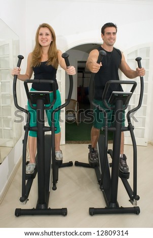 Young, attractive couple working out at the gym together. Vertically composed shot taken from directly in front of the couple.