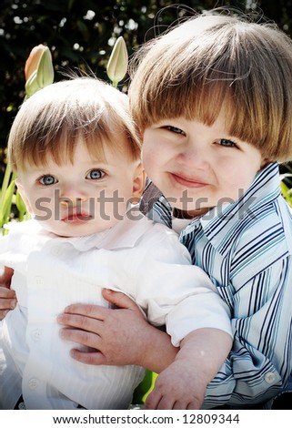 Vertically framed shot of two young brothers hugging each other outdoors.