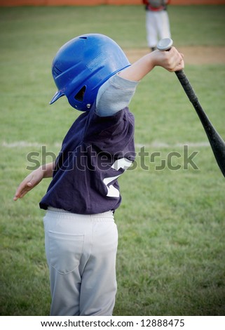 Young boy taking some practice swings as he prepares to go to the plate to hit