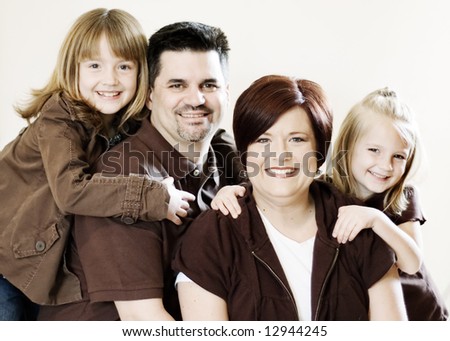 Family of four posing together in a studio. Horizontally framed shot against a clean studio background
