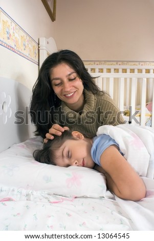 Vertically framed shot of a mother putting her daughter to bed.