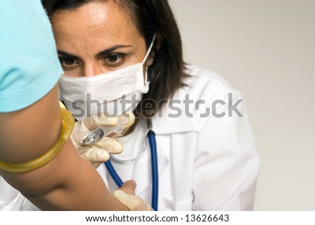 Female doctor wearing a mask concentrates while giving a shot in the arm to a patient. horizontally framed shot