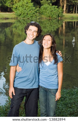 Happy, laughing couple standing in front of a pond. Vertical