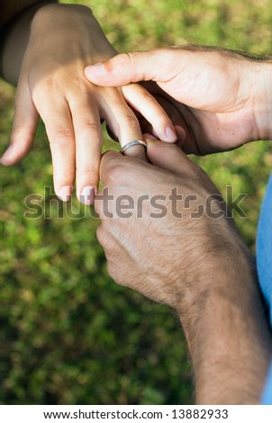 Man placing an engagement ring on a woman's ring finger-Vertically framed photograph