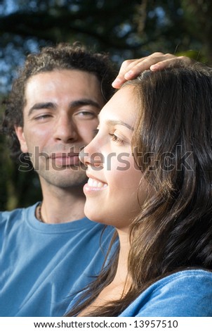 Man lovingly touches woman's head as she smiles. Vertically framed photograph