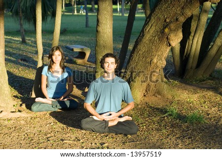 Couple sitting cross legged practicing yoga as they stare straight ahead. Horizontally framed photograph