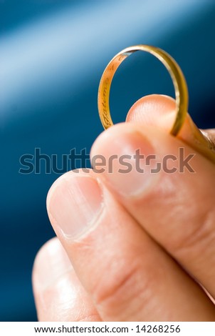 A hand offering a golden ring that is engraved in the inside. - vertically framed